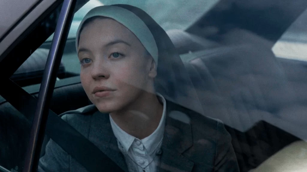 Sydney Sweeney vestida de noviça. Ela está dentro de um carro e a imagem do vidro refletindo sua viagem | Imaculada (2024)

