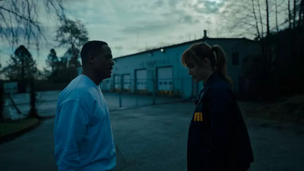 Ator Blair Underwood está falando com atriz Maika Monroe, que está de cabeça baixa enquanto o escuta falar | Questão D