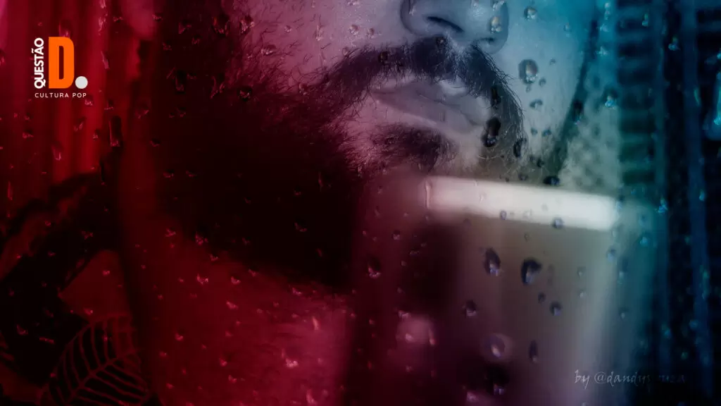 Bear - Igor Cabrado | Queixo de um homem barbudo, sério, segurando um celular. Efeito Dutone e de chuva no vidro | Questão D 