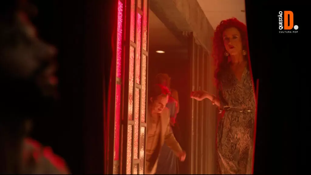 Welcome to Chippendales (2022): Corpo, Fetiche e Fio-dental | Cena da série em que Denise (Juliette Lewis) está andando no corredor iluminado e o vestiário escuro  | Questão D